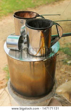 Pot of hot water boiler on wood fueled stove with coffee filter strainer bag. Traditional way to make Laos styled coffee called Kafe Lao and tea
