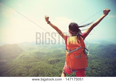 young asian woman hiker enjoy the view on mountain peak cliff