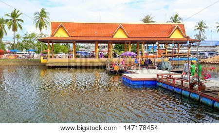 riverside water market at Ranot, Thailand, with customers visiting vendor stalls on boats and floating platforms