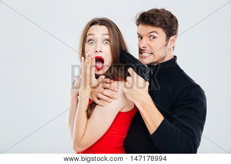 Mad criminal young man threatening to scared young woman with gun