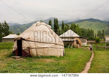 KEMIN, KYRGYZSTAN - AUGUST 2, 2013: Unidentified children go away past Central Asian yurt village house on August 2, 2013 in Kyrgyzstan. Kyrgyzstan's population is 5.4 million