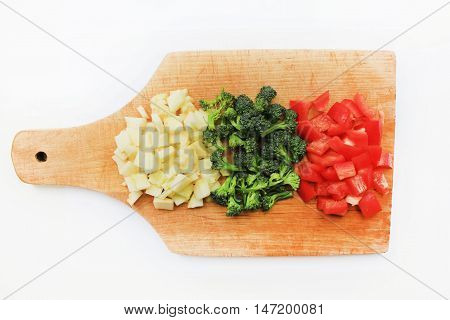 Fresh organic chopped sliced vegetables on cutting board broccoli red bell pepper and squash cooking ingredients for homemade vegetarian meal isolated on white background Healthy eating diet food concept