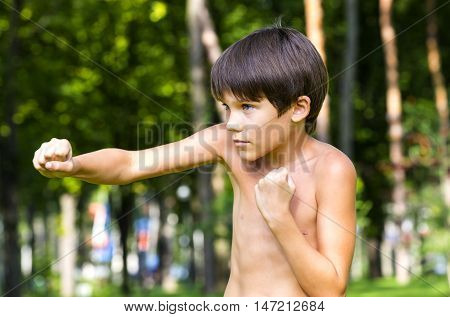 portrait of a boy in nature which shows his muscles