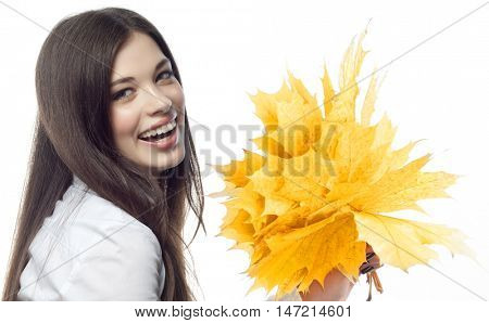 closeup portrait of attractive  caucasian smiling woman brunette isolated on white studio shot lips toothy smile face hairlooking at camera tooth hand holding yellow marple autumn leaves