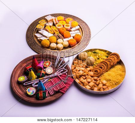 indian sweet food served with assorted fire crackers in separate plate showing diwali concept