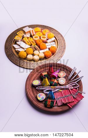indian sweet food served with assorted fire crackers in separate plate showing diwali concept