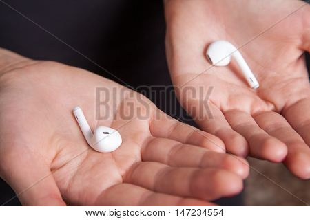 Wireless earphones on human hands. studio shot.