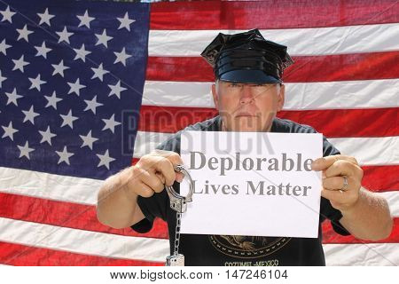 A man poses in front of am American flag with a Deplorable Lives Matter sign.
With his dog.