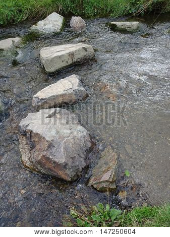 Stepping stones across river waterfall landscape photographed at Colby Woodland Garden near Amroth in Pembrokeshire