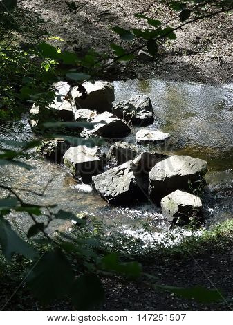 Stepping stones across river waterfall landscape photographed at Colby Woodland Garden near Amroth in Pembrokeshire