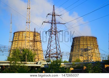 Two cooling pipes, power lines and pipes with hot water clear blue sky