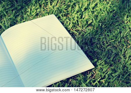 open notebook on grass field in park (vintage background)