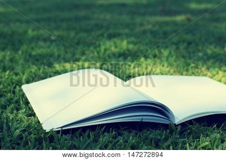 open notebook on grass field in park (vintage background)