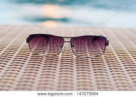 closeup Sunglasses on wooden table and river (vintage background)