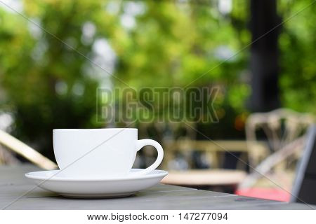 Coffee cup on table in garden (vintage background)
