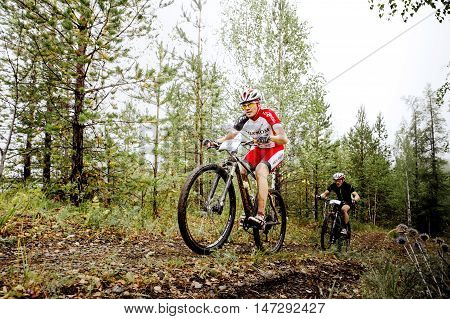 Revda Russia - July 31 2016: two men athletes cyclists ride along a forest trail during Regional competitions on cross-country bike
