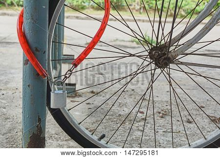 Red chain and silver colored lock on bicycle wheel.
