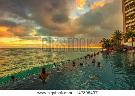 Waikiki Oahu Hawaii - August 20 2016: people of infinity edge swimming pool looking at the ocean twilight. Sheraton Waikiki Hotel in Waikiki Beach Honolulu. Summertime relaxing in luxury resort.