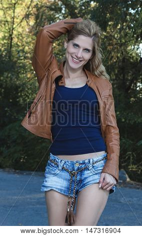 blonde girl in a brown leather jacket and denim shorts