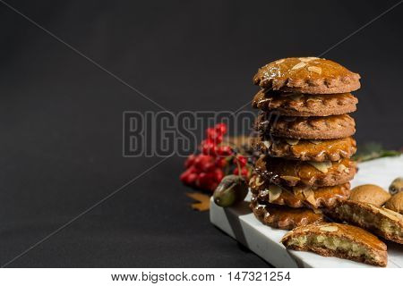 Typical Dutch filled spicy cookies with almonds on autumn colored and dark background