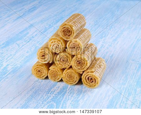 Wafer rolls on a wooden blue background. Wafer rolls are folded house.