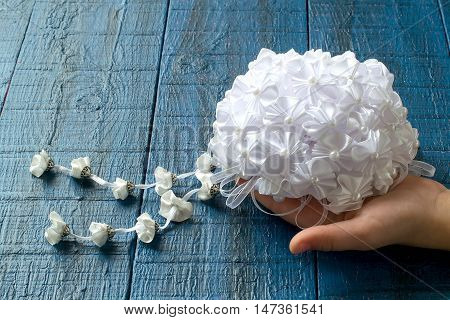 Making beautiful bows for decoration hair and gifts in the art kanzashi. Step by step photo instructions. Step 6. Ready bow of the details in the shape of a flower with pendants in a child's hands