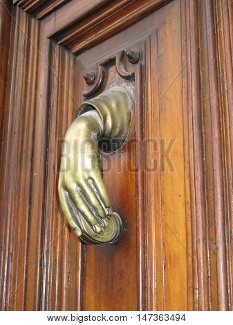 Door hand knocker old in a female hand, on the old wodden door.