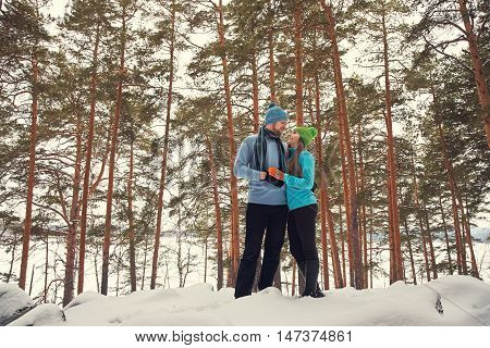 Young happy couple in love in the winter forest. Man and woman outdoors