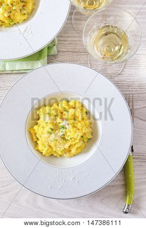 Yellow risotto with saffron cheese and onion shallot plant and wineglass