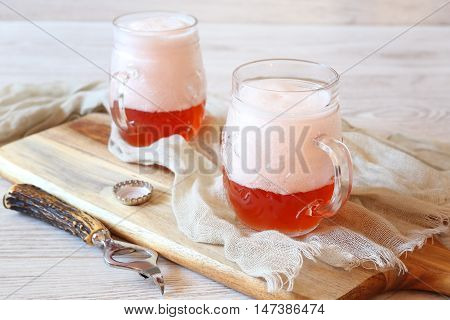 Two mugs of light fruit beer with foam cap