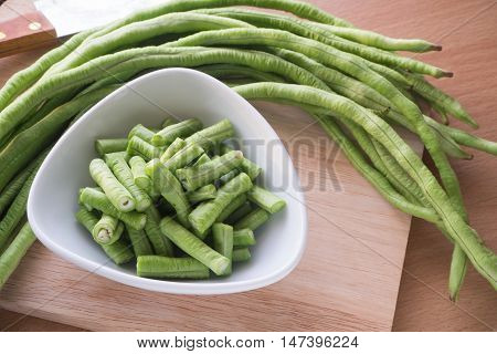 Sliced yard long bean vegetable on the white dish and wooden block Asian's homegrown vegetable View from top vegetable.