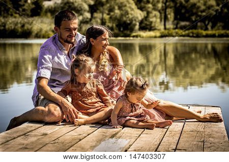 Young Family On Pier Near Lake