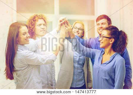 business, office, gesture and startup concept - smiling creative team doing high five gesture in office