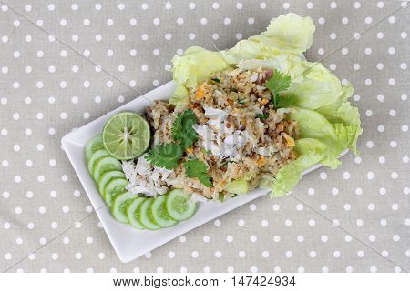 Fried rice with crab topped streamed crab,halve green lemon,sliced cucumber,lettuce and coriander  on gray. Top view