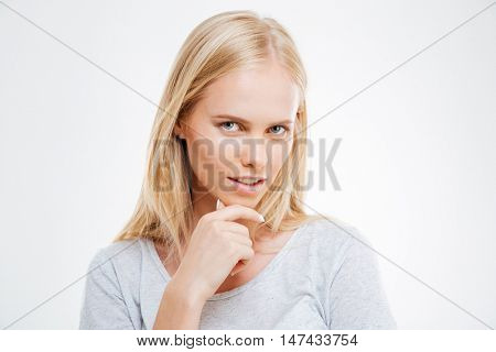 Close-up portrait of a pensive thougtful pretty blonde girl thinking about something isolated on the blue background