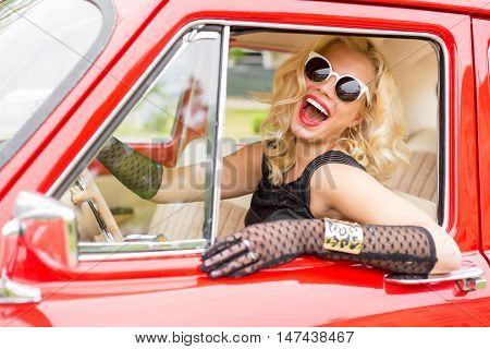 Funny woman with stylish sun-glasses driving a car