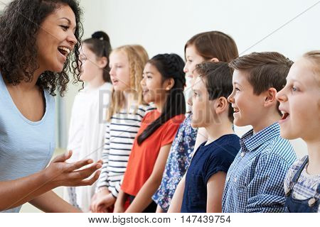 Children In School Choir Being Encouraged By Teacher