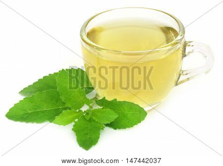 Herbal tea in a cup with tulsi leaves over white background
