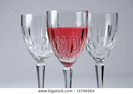 Tres vasos de cristal con enfoque selectivo. Uno con vino Zinfandel. Composición sobre una espalda neutral