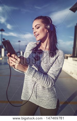 Excited woman listening music at park house in downtown searching playlist on tablet playing or messaging outdoor