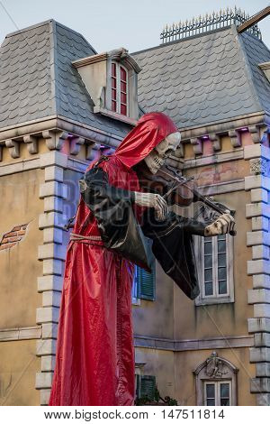 10th September 2016, Bad Dürkheim, folk festival 2016, Germany: Mysterious red hooded skeleton figure playing violin in front of a mystic castle in the amusement park