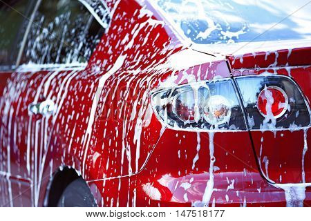 Car washing concept. Red car in foam