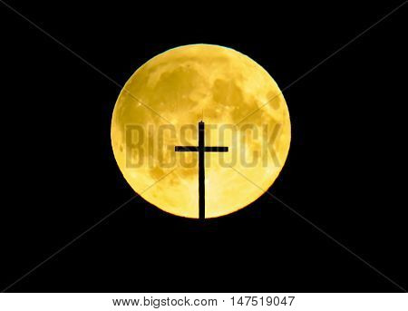 A big yellow full moon with a church's cross infront it.