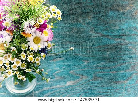 Bouquet of fresh summer flowers on the blue wooden grunge desk. Mock up for greeting cards, holiday postcards, invintation and anniversary celebration in vintage hipster style with copy space