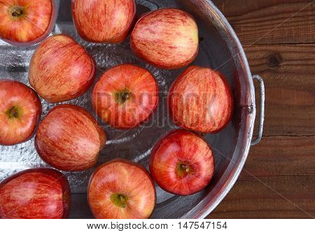 High angle closeup of a metal tub filled with water and apples for the Halloween custom of Apple Bobbing.