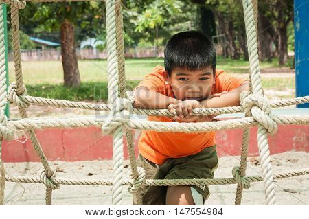 cute asian boy sitting alone at playground