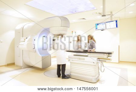 X-ray tomography scanner machine with blurred figures of doctor, nurse and patient in a modern hospital.