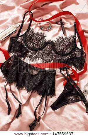 Lacy underwear on the bed is decorated with a red ribbon with perfume pamada and decorations.