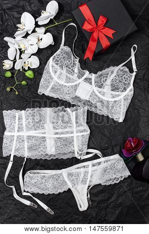 Beautiful white lace lingerie on the wrapping paper. Next to the box flowers and perfume.