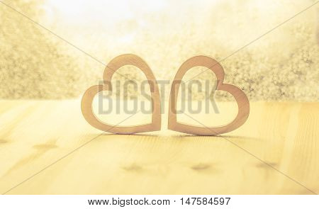 Wooden hearts on a shiny background - Romantic scenery with two hearts made from wood against a bright background